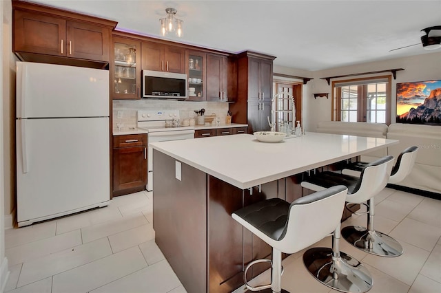 953 Tulip St, Deltona, FL 32725 - kitchen featuring white appliances, light countertops, tasteful backsplash, glass insert cabinets, and a kitchen breakfast bar