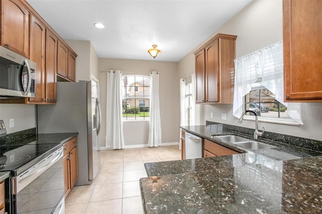 201 Dyson Dr, Deland, FL 32724 - kitchen featuring stainless steel appliances, a sink, brown cabinetry, dark stone counters, and light tile patterned floors