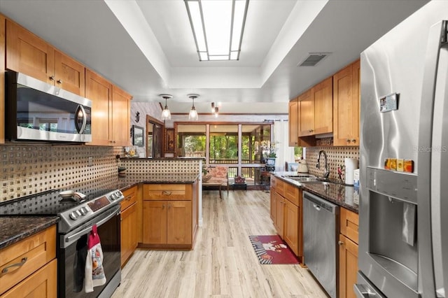 96 Hollow Branch Xing, Ormond Beach, FL 32174 - kitchen with appliances with stainless steel finishes, a sink, light wood finished floors, a peninsula, and backsplash