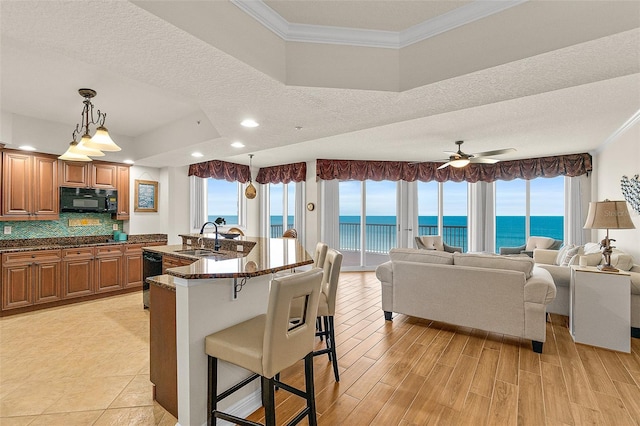 2901 S Atlantic Ave Unit 401, Daytona Beach Shores, FL 32118 - kitchen with black appliances, crown molding, a breakfast bar, a water view, and brown cabinets