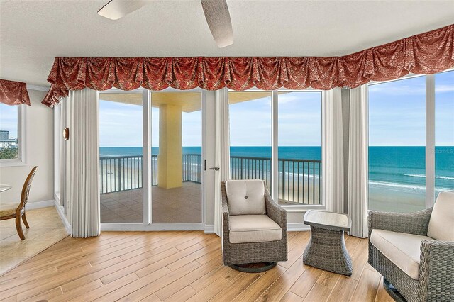 2901 S Atlantic Ave Unit 401, Daytona Beach Shores, FL 32118 - living area featuring light wood-style flooring, view of water and beach, baseboards, and a textured ceiling