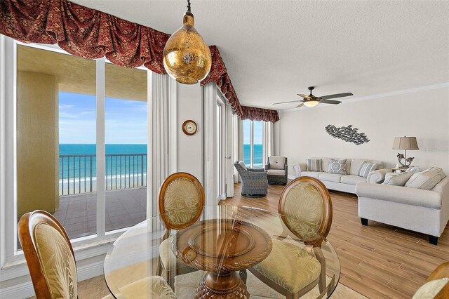 2901 S Atlantic Ave Unit 401, Daytona Beach Shores, FL 32118 - dining room with light wood-style floors, a water view, a ceiling fan, a textured ceiling, and crown molding