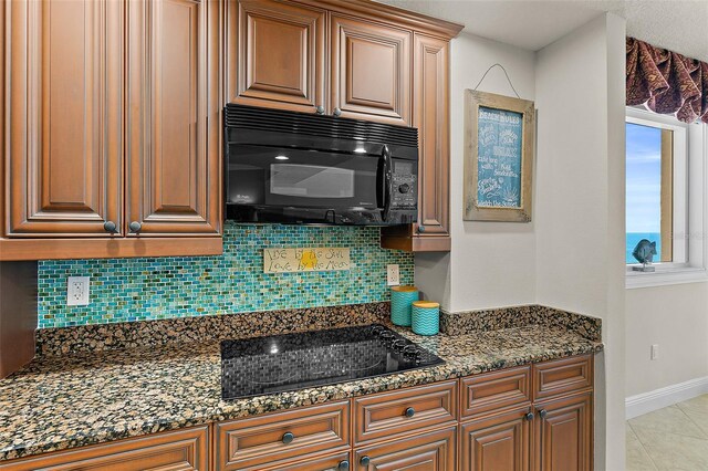 2901 S Atlantic Ave Unit 401, Daytona Beach Shores, FL 32118 - kitchen with black appliances, backsplash, dark stone counters, baseboards, and brown cabinetry
