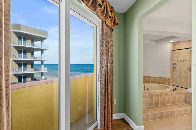 2901 S Atlantic Ave Unit 401, Daytona Beach Shores, FL 32118 - full bathroom featuring a bath, a water view, baseboards, and plenty of natural light