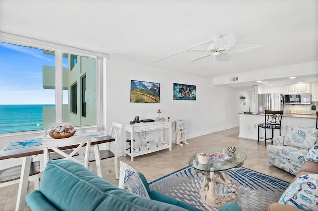 2987 S Atlantic Unit 606, Daytona Beach Shores, FL 32118 - living room with ceiling fan, a water view, baseboards, and a textured ceiling