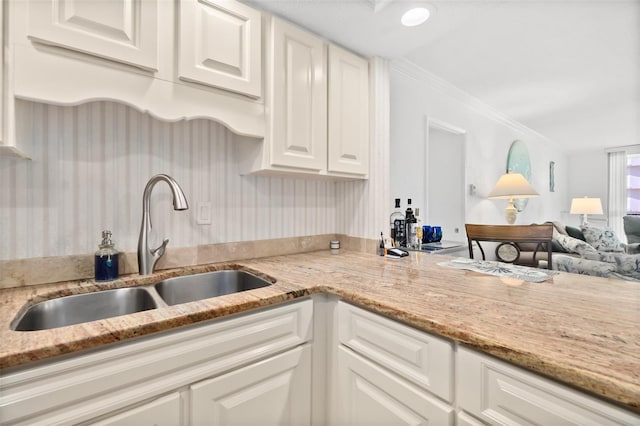2987 S Atlantic Unit 606, Daytona Beach Shores, FL 32118 - kitchen with a sink, white cabinetry, light stone counters, open floor plan, and crown molding