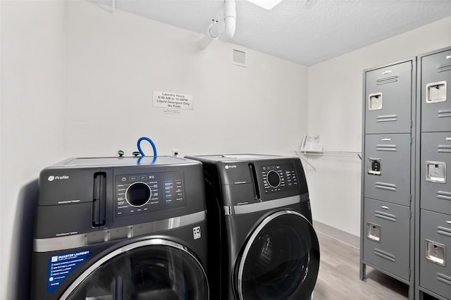 2987 S Atlantic Unit 606, Daytona Beach Shores, FL 32118 - washroom featuring washer and clothes dryer, light wood-type flooring, and a textured ceiling