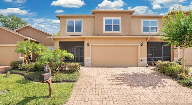 302 Tammie Sue Ln, Deland, FL 32724 - view of front of property with a sunroom, decorative driveway, stucco siding, and an attached garage