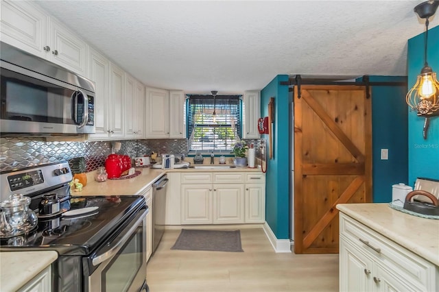 625 N Halifax Ave Unit 11, Daytona Beach, FL 32118 - kitchen featuring appliances with stainless steel finishes, a sink, light wood-type flooring, a barn door, and light countertops