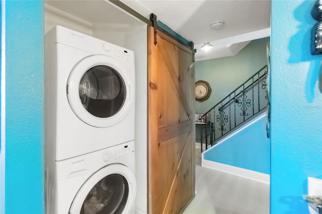 625 N Halifax Ave Unit 11, Daytona Beach, FL 32118 - laundry room with stacked washer and clothes dryer, a barn door, and wood finished floors