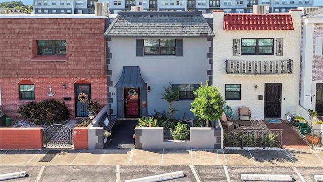 625 N Halifax Ave Unit 11, Daytona Beach, FL 32118 - view of property featuring uncovered parking, stucco siding, a gate, brick siding, and mansard roof