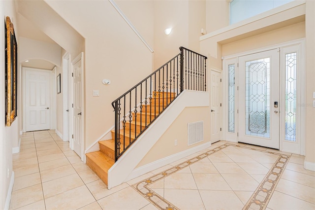 4427 S Atlantic Ave, Port Orange, FL 32127 - foyer with stairs, arched walkways, baseboards, light tile patterned floors, and a high ceiling