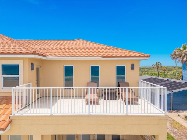 4427 S Atlantic Ave, Port Orange, FL 32127 - rear view of property featuring a balcony, a tile roof, and stucco siding