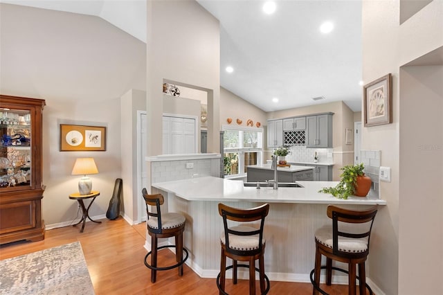 1637 Bent Oaks Blvd, Deland, FL 32724 - kitchen with gray cabinets, lofted ceiling, a sink, tasteful backsplash, and a kitchen breakfast bar