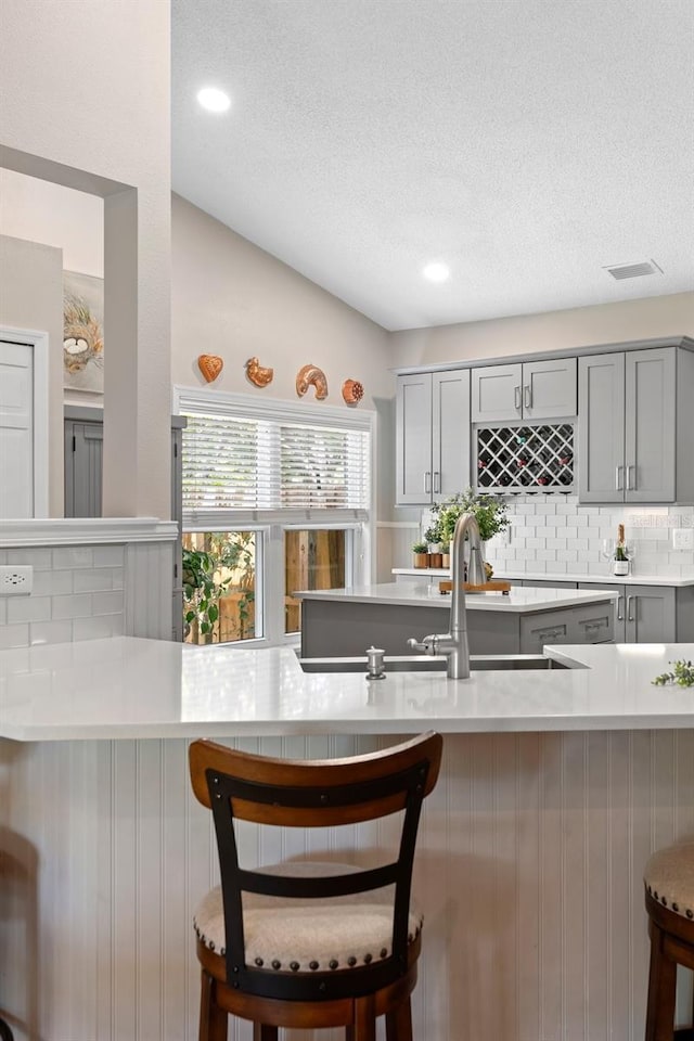1637 Bent Oaks Blvd, Deland, FL 32724 - kitchen featuring gray cabinetry, light countertops, decorative backsplash, a textured ceiling, and a kitchen breakfast bar