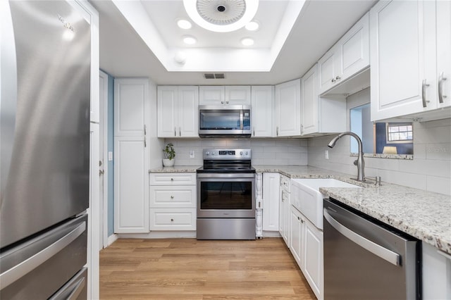5 Greenfern Cir, Ormond Beach, FL 32174 - kitchen featuring appliances with stainless steel finishes, a raised ceiling, tasteful backsplash, white cabinets, and light stone counters