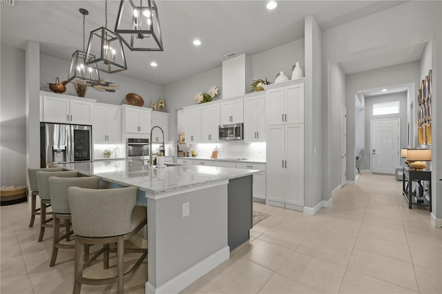 344 Stirling Bridge Dr, Ormond Beach, FL 32174 - kitchen featuring stainless steel appliances, a spacious island, white cabinets, pendant lighting, and a breakfast bar area