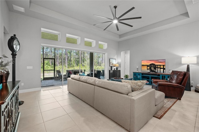 344 Stirling Bridge Dr, Ormond Beach, FL 32174 - living area with a tray ceiling, a ceiling fan, a towering ceiling, light tile patterned floors, and baseboards