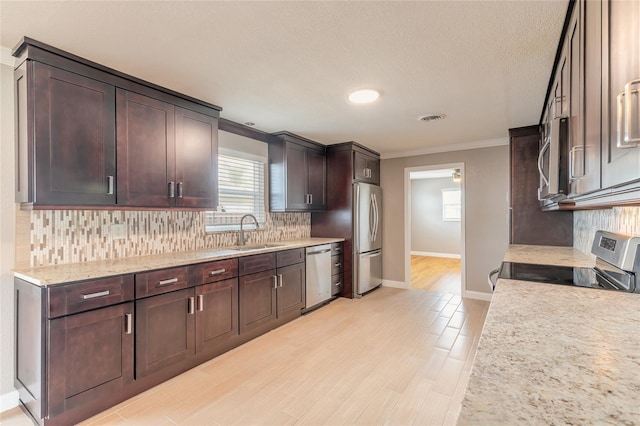 1032 Bel Aire Dr, Daytona Beach, FL 32118 - kitchen with appliances with stainless steel finishes, a sink, crown molding, dark brown cabinets, and backsplash