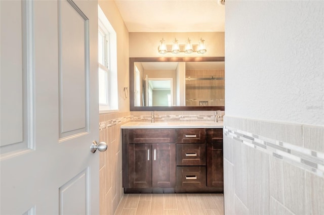 1032 Bel Aire Dr, Daytona Beach, FL 32118 - full bathroom with double vanity, tiled shower, tile walls, and a wainscoted wall
