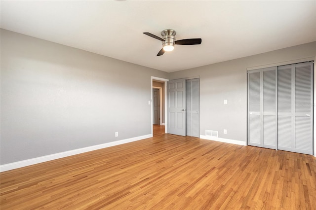1032 Bel Aire Dr, Daytona Beach, FL 32118 - unfurnished bedroom featuring two closets, baseboards, light wood-style flooring, and ceiling fan