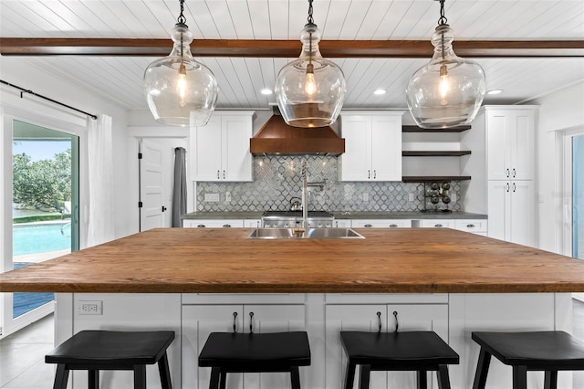 604 Springdale Dr, Flagler Beach, FL 32136 - kitchen featuring wall chimney exhaust hood, butcher block countertops, decorative backsplash, wood ceiling with exposed beams, and an island with sink