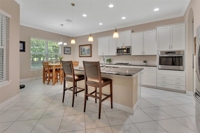 171 Birchmont Dr, Deland, FL 32724 - kitchen featuring appliances with stainless steel finishes, ornamental molding, dark stone countertops, a sink, and a breakfast bar area