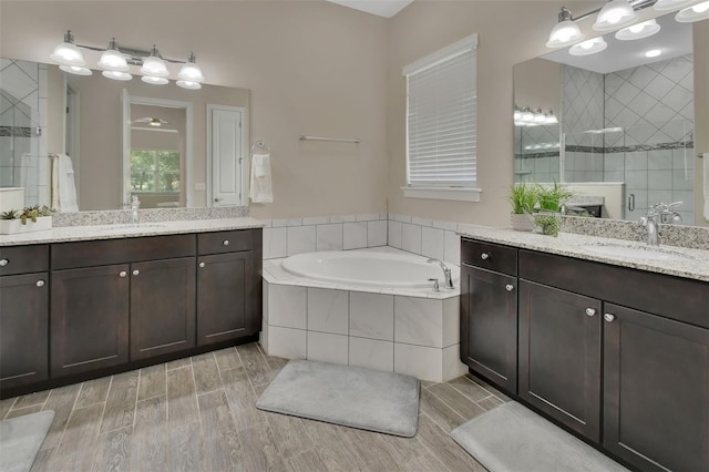 171 Birchmont Dr, Deland, FL 32724 - bathroom with two vanities, a garden tub, a tile shower, and wood finished floors