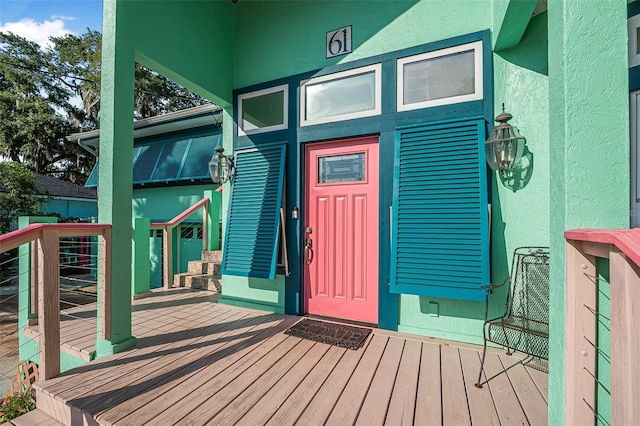 61 E Bayshore Dr, Port Orange, FL 32127 - view of exterior entry featuring stucco siding and a wooden deck