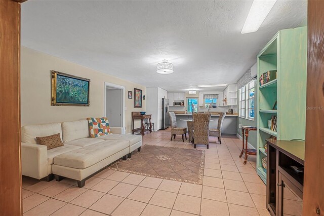 61 E Bayshore Dr, Port Orange, FL 32127 - living room featuring light tile patterned flooring, a textured ceiling, and baseboards