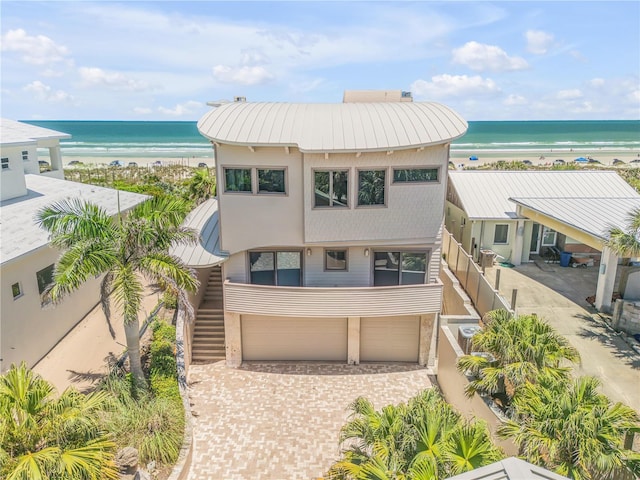 1209 N Atlantic Ave, New Smyrna Beach, FL 32169 - view of front facade featuring metal roof, view of water and beach, an attached garage, stairway, and a standing seam roof