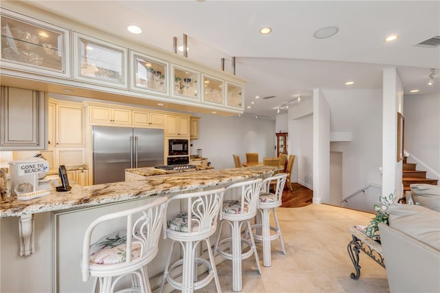 1209 N Atlantic Ave, New Smyrna Beach, FL 32169 - kitchen with cream cabinetry, built in appliances, light stone countertops, a peninsula, and glass insert cabinets