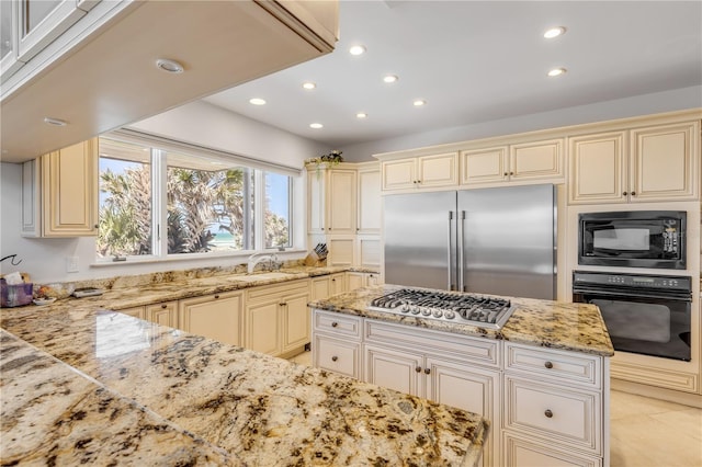 1209 N Atlantic Ave, New Smyrna Beach, FL 32169 - kitchen with cream cabinets, black appliances, light stone countertops, recessed lighting, and a sink