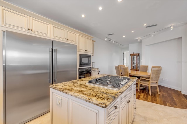 1209 N Atlantic Ave, New Smyrna Beach, FL 32169 - kitchen with black appliances, cream cabinetry, light stone counters, a center island, and recessed lighting