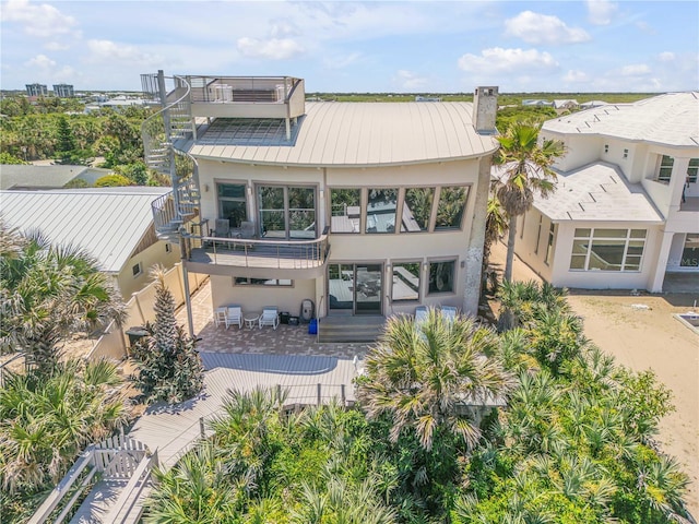 1209 N Atlantic Ave, New Smyrna Beach, FL 32169 - back of property featuring stucco siding, a balcony, a standing seam roof, metal roof, and stairs