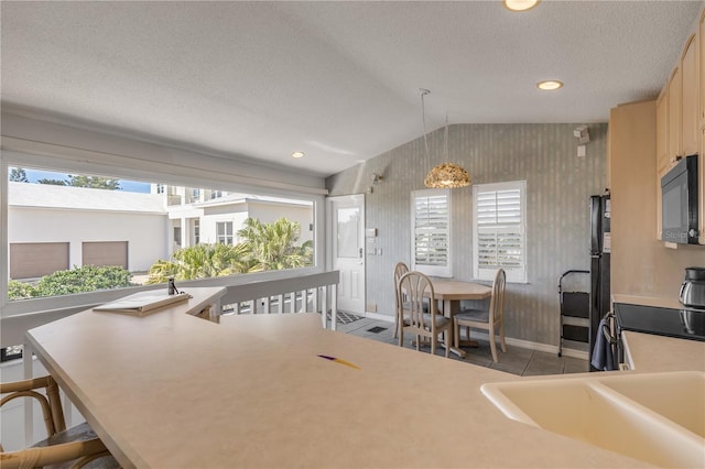 1209 N Atlantic Ave, New Smyrna Beach, FL 32169 - kitchen featuring lofted ceiling, black appliances, baseboards, a textured ceiling, and a kitchen bar