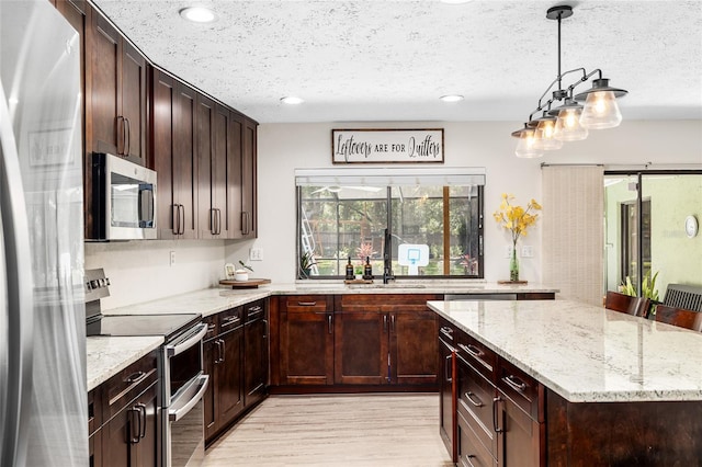 4301 Hudson Ln, Tampa, FL 33618 - kitchen featuring appliances with stainless steel finishes, light wood-style flooring, light stone counters, a textured ceiling, and a kitchen island