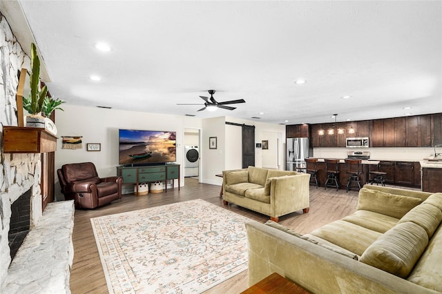4301 Hudson Ln, Tampa, FL 33618 - living area featuring washer / dryer, a barn door, a stone fireplace, light wood-type flooring, and recessed lighting