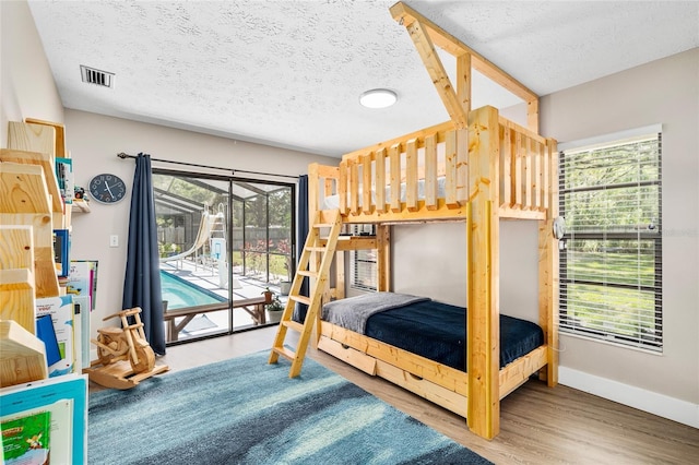 4301 Hudson Ln, Tampa, FL 33618 - bedroom featuring access to outside, a textured ceiling, wood finished floors, and baseboards