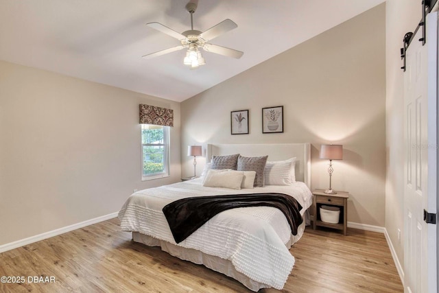 706 Fox Tail Ct, New Smyrna Beach, FL 32168 - bedroom with light wood-style flooring, baseboards, vaulted ceiling, a barn door, and ceiling fan