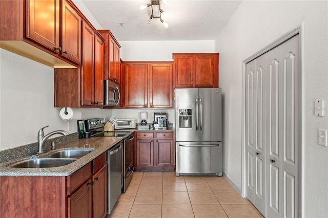 1469 Broken Oak Dr Unit 43A, Winter Garden, FL 34787 - kitchen with stainless steel appliances, a sink, dark stone countertops, light tile patterned flooring, and brown cabinetry