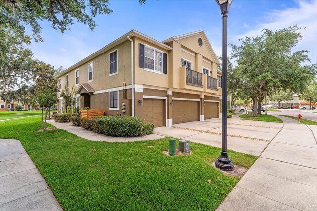 1469 Broken Oak Dr Unit 43A, Winter Garden, FL 34787 - view of property exterior featuring an attached garage, driveway, stucco siding, a yard, and a balcony
