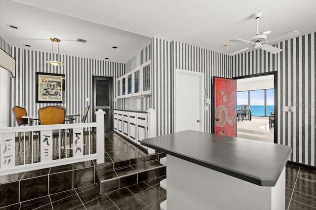 915 Ocean Shore Blvd Unit 8010, Ormond Beach, FL 32176 - kitchen with wallpapered walls, dark tile patterned floors, a ceiling fan, a kitchen island, and dark countertops
