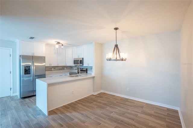 15 Misners Trl, Ormond Beach, FL 32174 - kitchen with appliances with stainless steel finishes, a chandelier, backsplash, light wood-style floors, and white cabinets