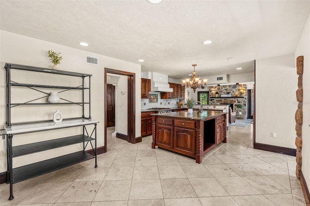5366 N Lake Farms Rd, De Leon Springs, FL 32130 - kitchen with a chandelier, a kitchen island with sink, custom exhaust hood, recessed lighting, and hanging light fixtures