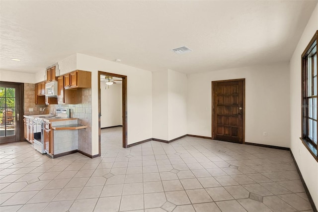 5366 N Lake Farms Rd, De Leon Springs, FL 32130 - kitchen featuring range with electric cooktop, white microwave, light countertops, backsplash, and light tile patterned floors