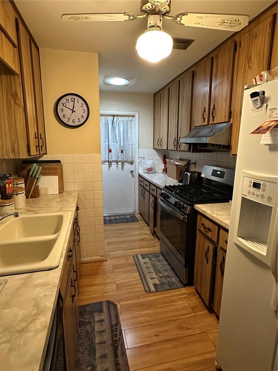 15555 SW 46th Cir, Ocala, FL 34473 - kitchen with stainless steel gas range, under cabinet range hood, white refrigerator with ice dispenser, light countertops, and light wood finished floors