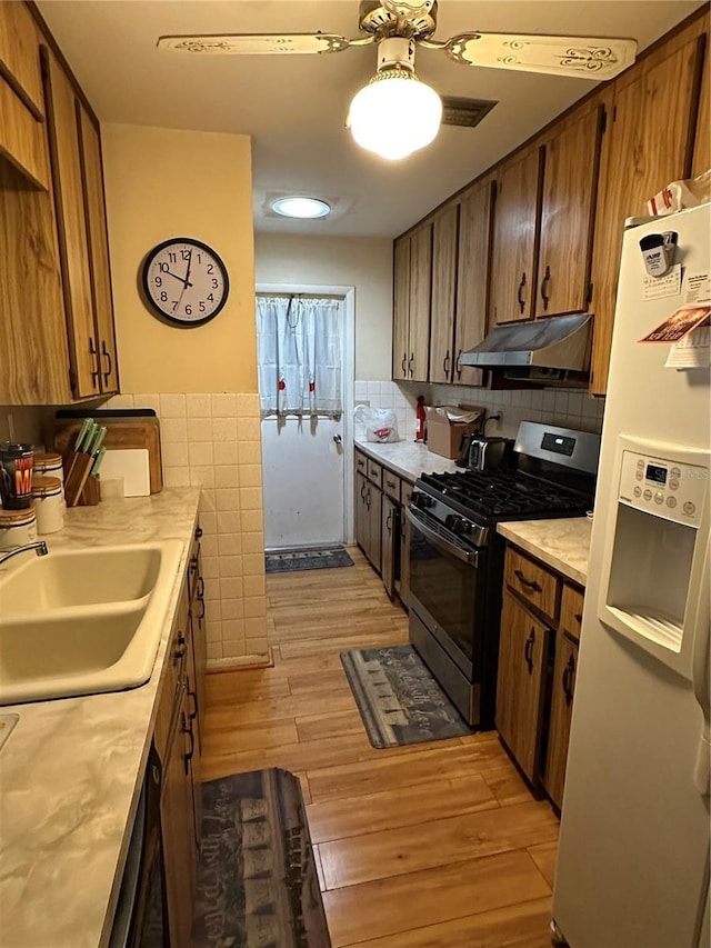 15555 SW 46th Cir, Ocala, FL 34473 - kitchen with stainless steel gas range, under cabinet range hood, white refrigerator with ice dispenser, light countertops, and light wood finished floors