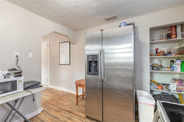449 3rd St, Daytona Beach, FL 32117 - kitchen with stainless steel refrigerator with ice dispenser, white microwave, light wood finished floors, and arched walkways
