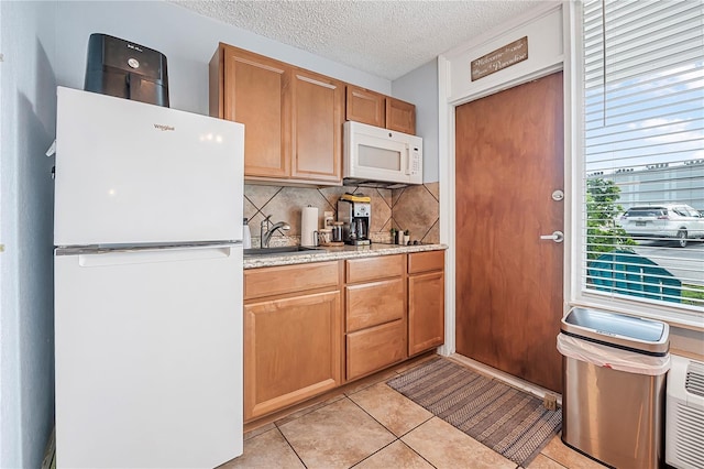 935 S Atlantic Ave Unit 105, Daytona Beach, FL 32118 - kitchen featuring white appliances, a sink, decorative backsplash, a textured ceiling, and light tile patterned flooring